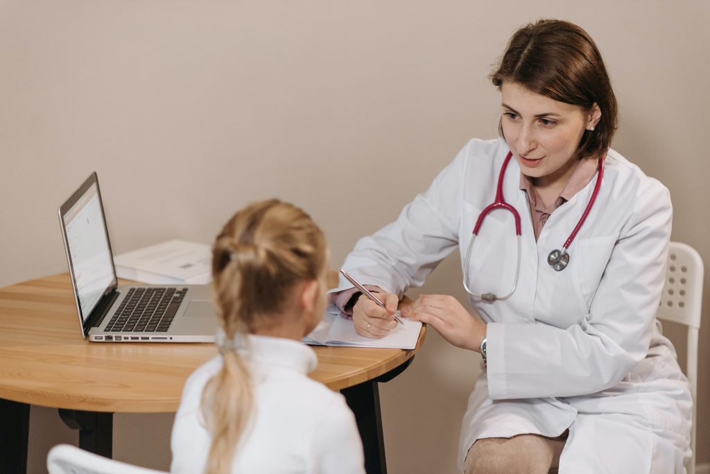 Doctor talking with a young girl at her desk